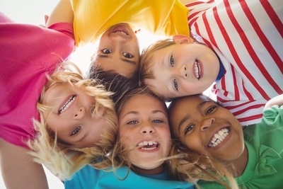 Fünf Kinder stecken in einem Kreis die Köpfe zusammen, so dass man ihre lachenden Gesichter sieht.