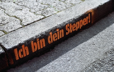 Auf einem Bordstein ist aufgesprüht Ich bin dein Stepper