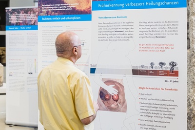 Ein älterer Mann betrachtet eine Ausstellungswand