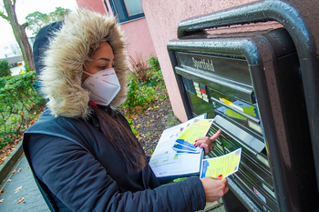 Eine Impflotsin wirft Infomaterial in einen Briefkasten.