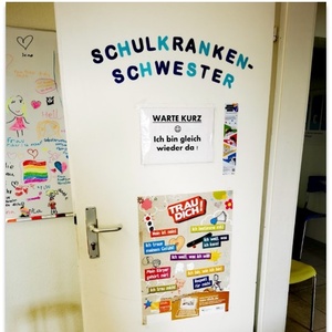 Eine Tür beklebt mit Plakaten und der Aufschrift " Schulkrankenschwester".