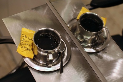 Eine Tasse Kaffee mit einem Keks steht vor einem Friseur-Spiegel