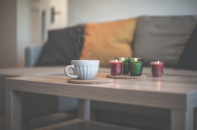 Eine Tasse Kaffee und mehrere Kerzen stehen auf einem Couchtisch.