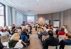 Ein Auditorium hört einem Redner zu. Blick von hinten.