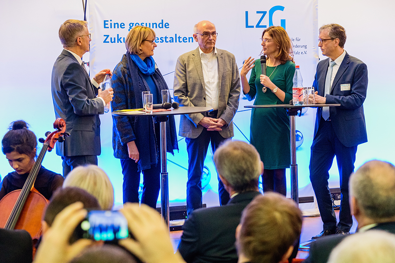 Zwei Frauen und drei Männer stehen in einer Runde und diskutieren
